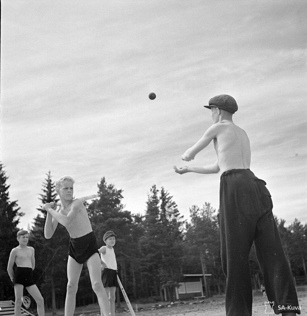 Toinen pojista syöttää kuvassa palloa ja toinen lyö.