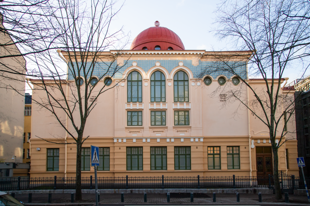 Värivalokuva Helsingin synagogasta. Rakennus on kolmikerroksinen rapattu tiilitalo, jossa on symmetrisesti suunniteltu julkisivu.